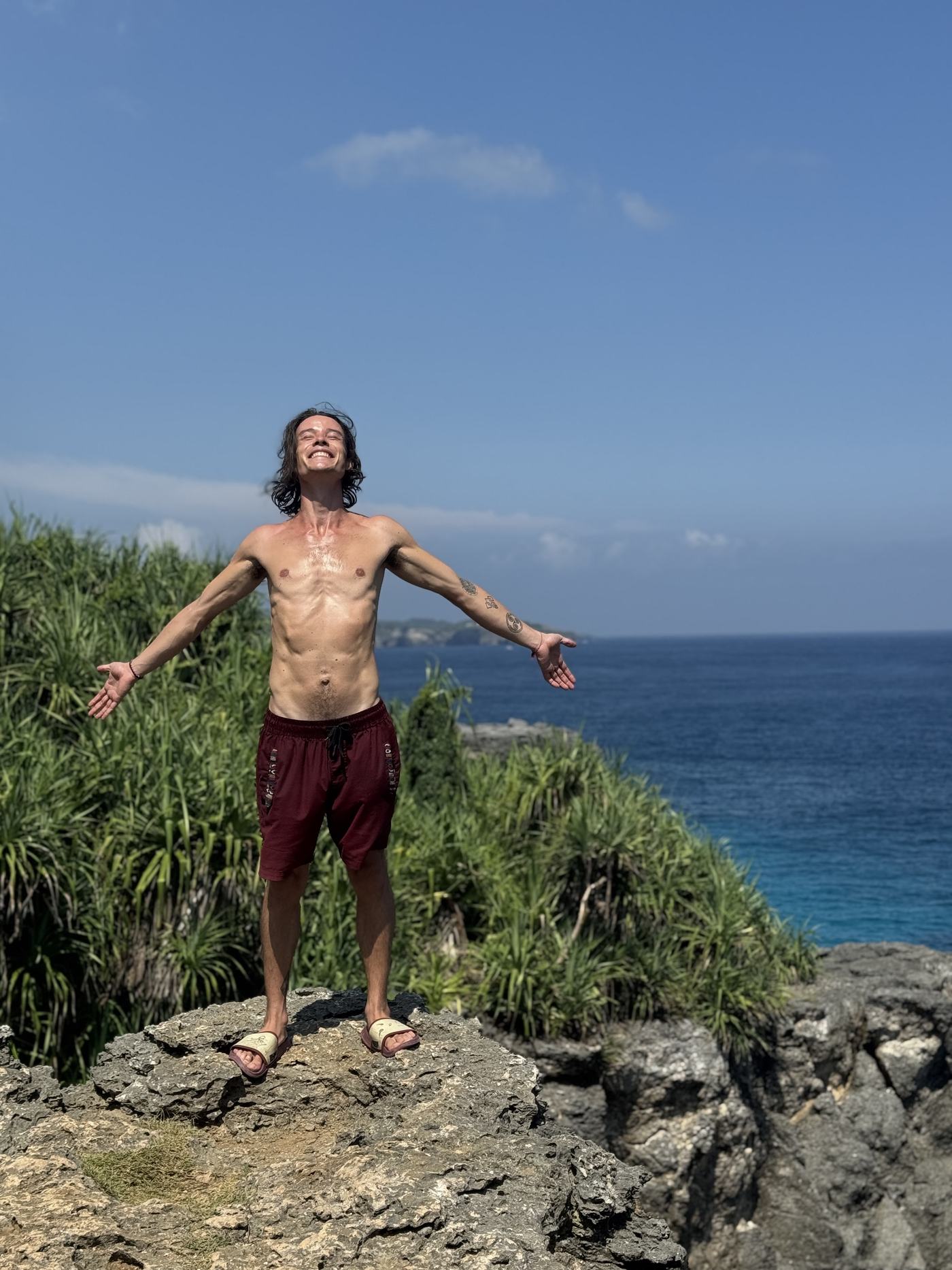 Aaron standing on a clifftop by the sea, arms open